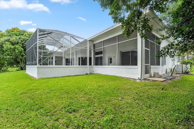 rear view of house featuring a lanai and a lawn