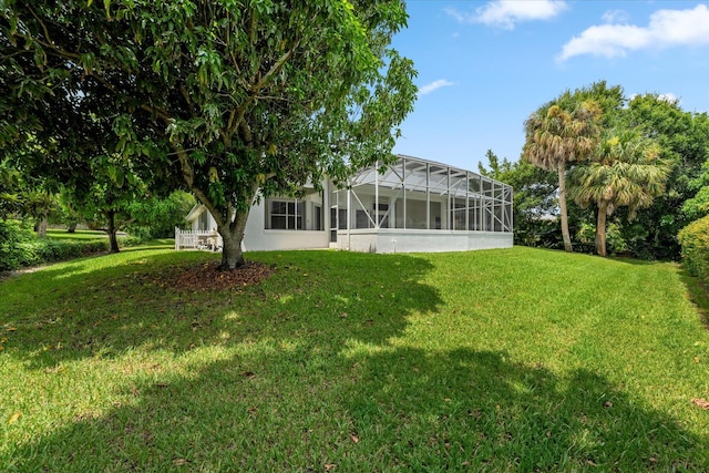 rear view of house featuring glass enclosure and a lawn