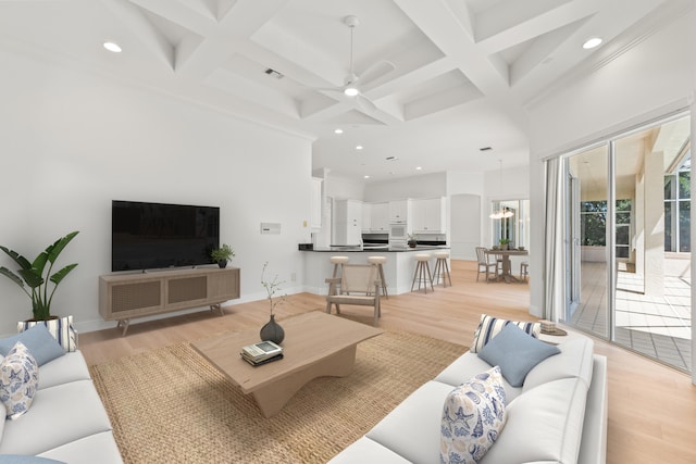 living room featuring coffered ceiling, beamed ceiling, ceiling fan with notable chandelier, light hardwood / wood-style floors, and ornamental molding