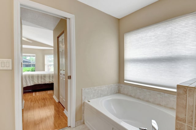 bathroom with vaulted ceiling, a bath to relax in, and hardwood / wood-style flooring