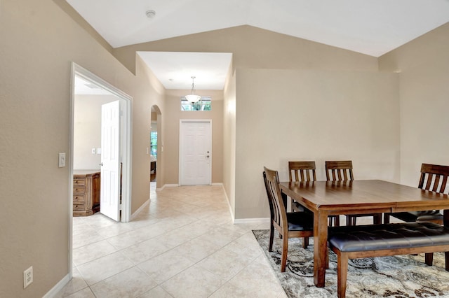 dining space featuring vaulted ceiling and light tile floors