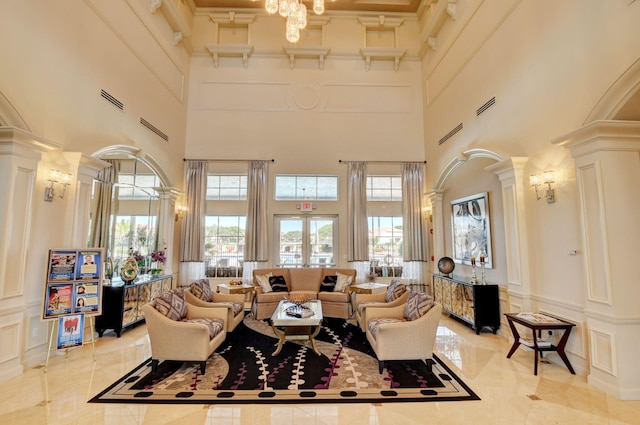 tiled living room featuring a high ceiling, french doors, an inviting chandelier, and ornate columns