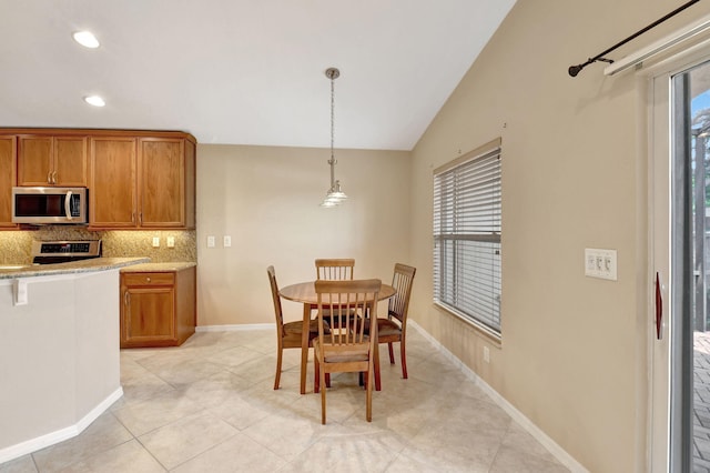 dining area with vaulted ceiling, plenty of natural light, and light tile floors