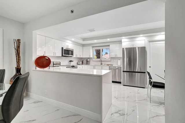 kitchen with appliances with stainless steel finishes, white cabinets, kitchen peninsula, tasteful backsplash, and light tile floors