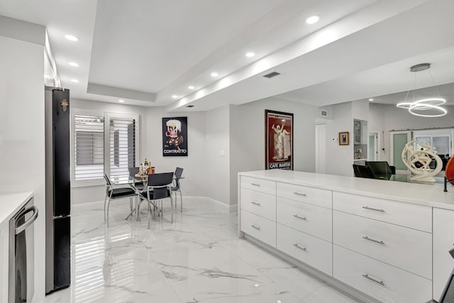 interior space featuring a tray ceiling, white cabinets, stainless steel refrigerator, pendant lighting, and light tile flooring