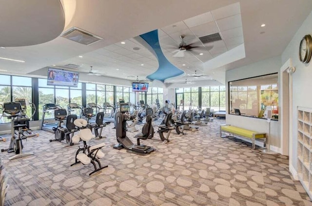 gym featuring a raised ceiling, ceiling fan, light colored carpet, and a drop ceiling