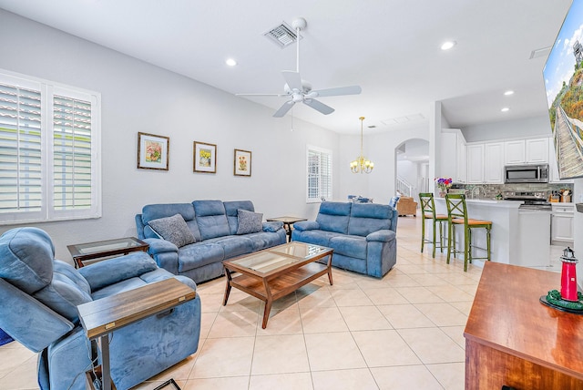 living room featuring ceiling fan with notable chandelier and light tile flooring