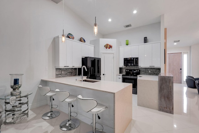 kitchen featuring white cabinetry, sink, kitchen peninsula, decorative light fixtures, and appliances with stainless steel finishes