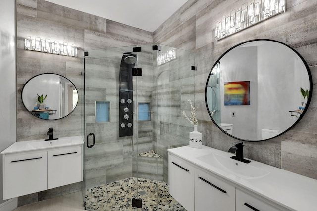 bathroom with vanity, tile walls, and a shower with shower door