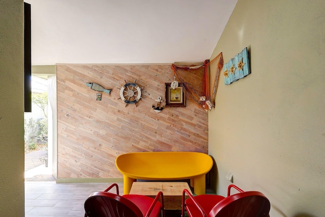 living area featuring lofted ceiling and wooden walls