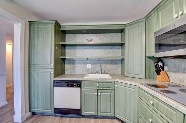 kitchen with tasteful backsplash, light wood-type flooring, green cabinets, sink, and white appliances