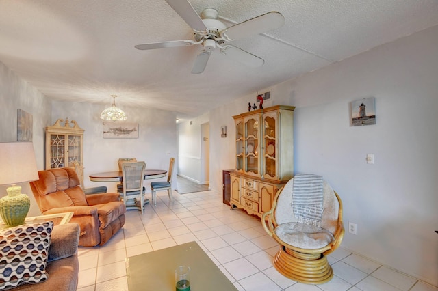 living room with a textured ceiling, ceiling fan, and light tile floors