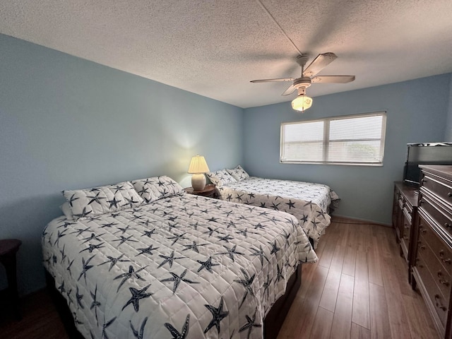 bedroom with dark wood-type flooring, ceiling fan, and a textured ceiling