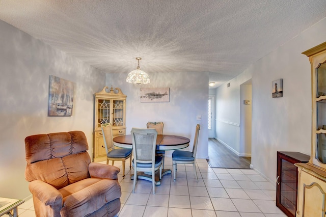 dining room with a notable chandelier, light hardwood / wood-style floors, and a textured ceiling