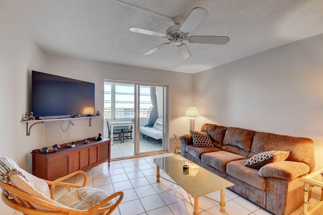 living room featuring ceiling fan, a textured ceiling, and light tile floors