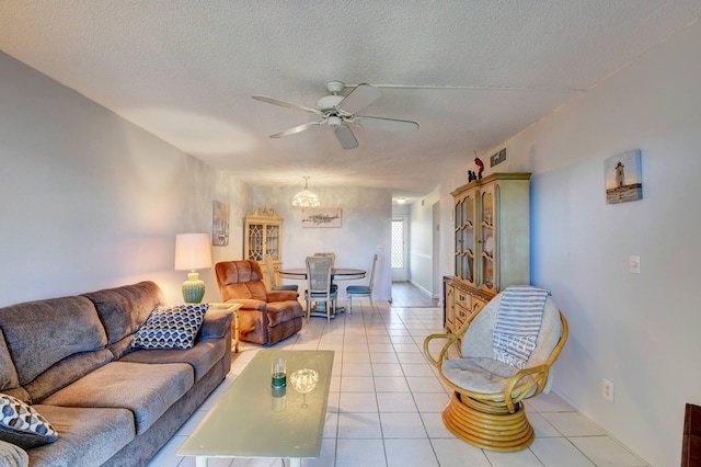 tiled living room featuring a textured ceiling and ceiling fan with notable chandelier