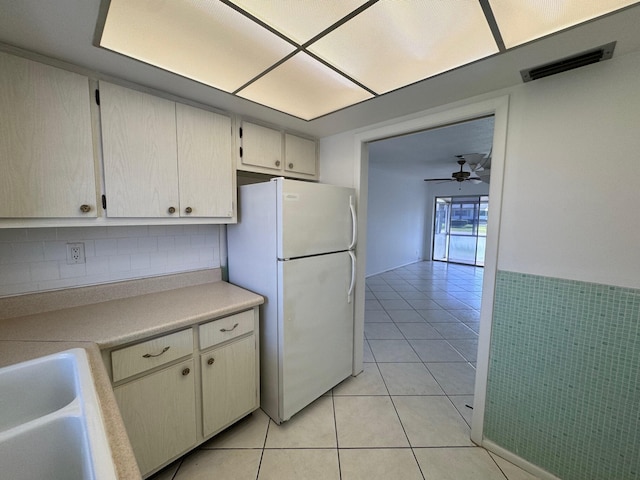 kitchen featuring tasteful backsplash, light tile flooring, ceiling fan, and white refrigerator