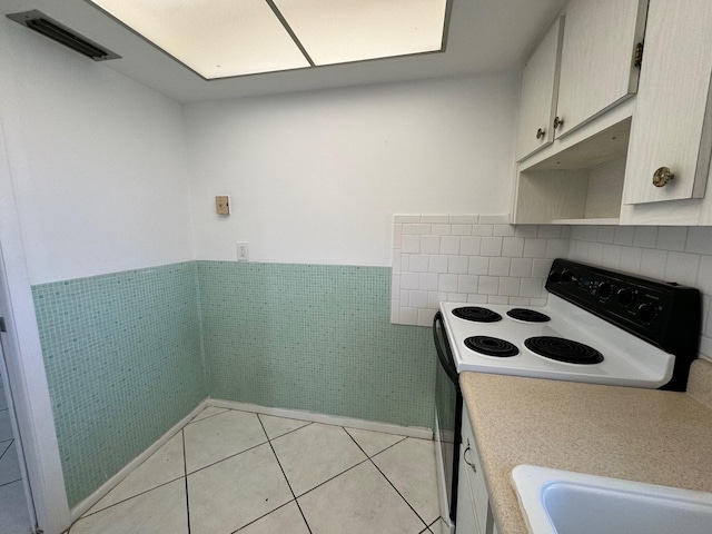 kitchen featuring light tile floors, white electric range oven, and tile walls