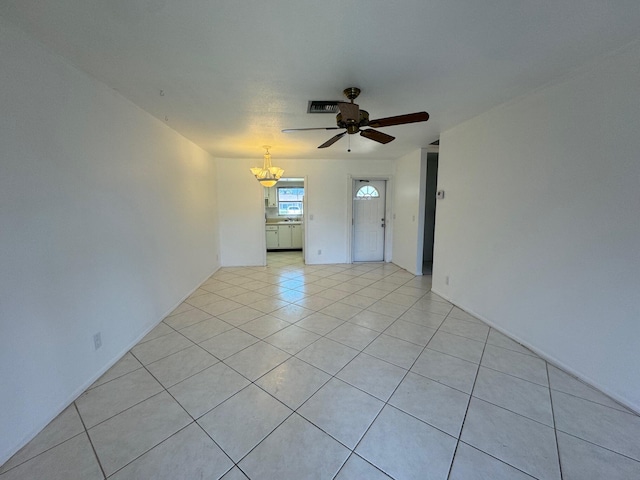 tiled empty room with ceiling fan with notable chandelier