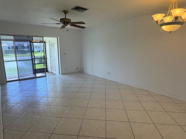 empty room featuring ceiling fan with notable chandelier and light tile floors