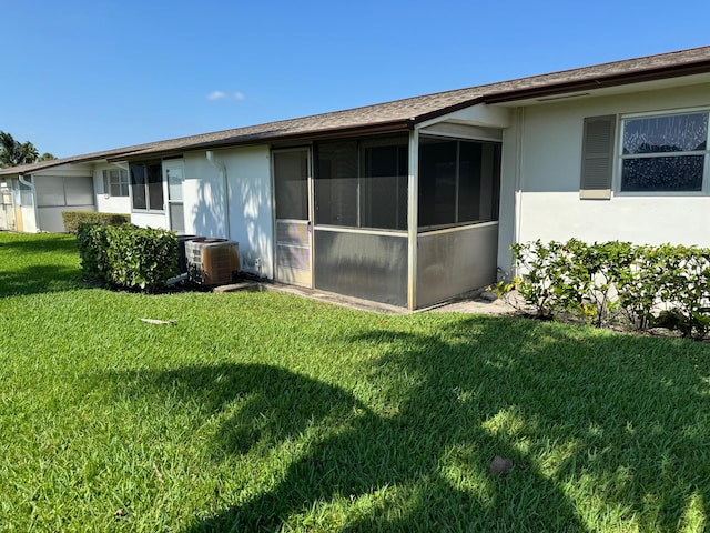 rear view of house with a lawn and central AC