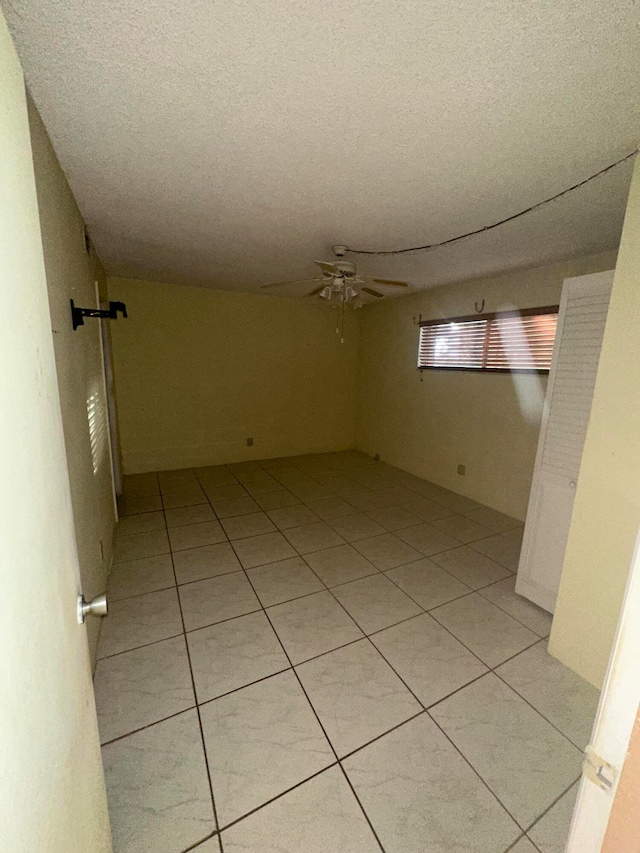 spare room featuring ceiling fan, a textured ceiling, and light tile flooring