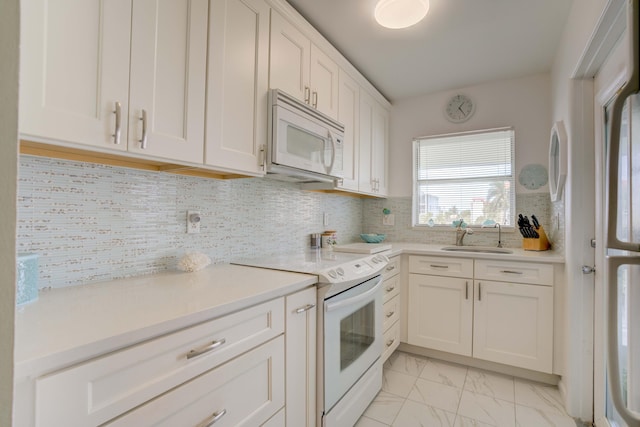 kitchen featuring white appliances, tasteful backsplash, white cabinetry, and sink