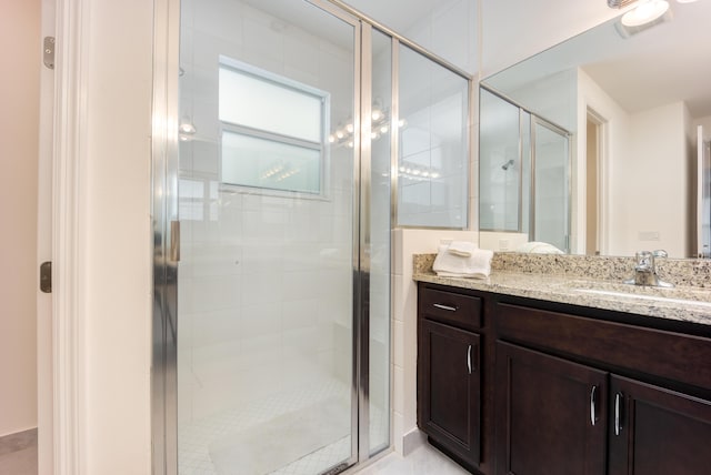 bathroom featuring a shower with door and vanity