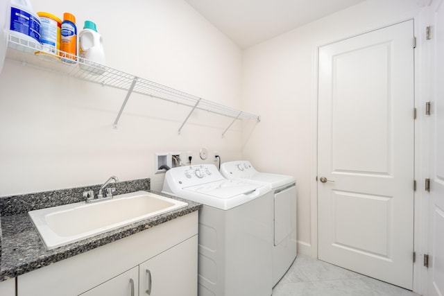 clothes washing area featuring separate washer and dryer, sink, and cabinets