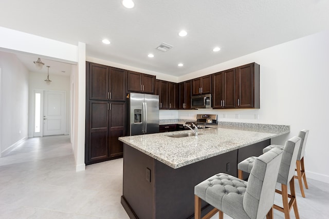 kitchen featuring light stone countertops, sink, stainless steel appliances, a kitchen breakfast bar, and kitchen peninsula