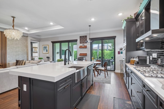 kitchen featuring dark hardwood / wood-style flooring, pendant lighting, a center island with sink, and wall chimney exhaust hood