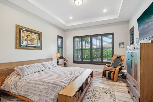 bedroom featuring light hardwood / wood-style floors and a tray ceiling