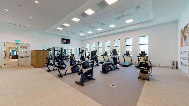 gym with light carpet, a drop ceiling, and a high ceiling