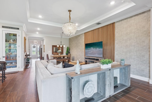 living room with a chandelier, a tray ceiling, and ornamental molding