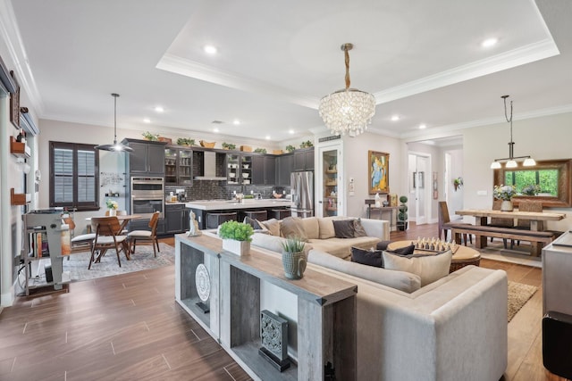 living room featuring crown molding, a notable chandelier, and a raised ceiling