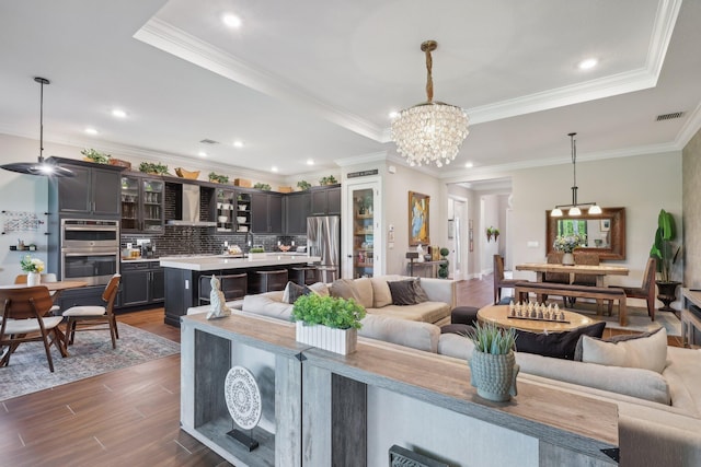 living room featuring crown molding, a notable chandelier, and a tray ceiling