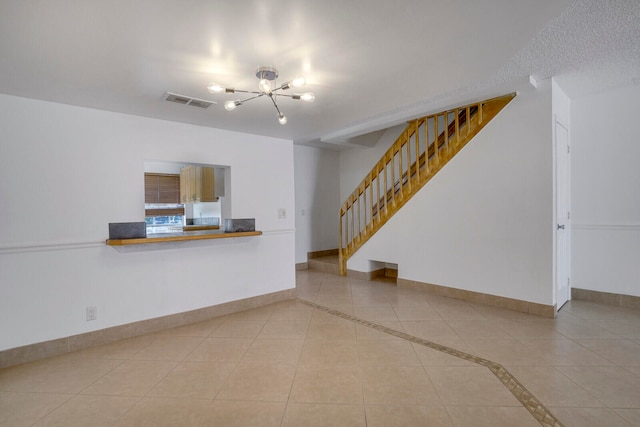 unfurnished living room featuring a chandelier and light tile floors