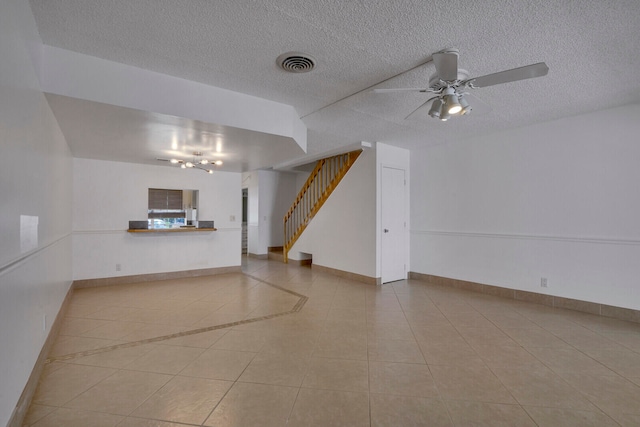 unfurnished living room featuring ceiling fan, a textured ceiling, and light tile floors