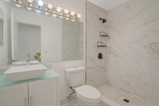 bathroom with a tile shower, vanity, and toilet