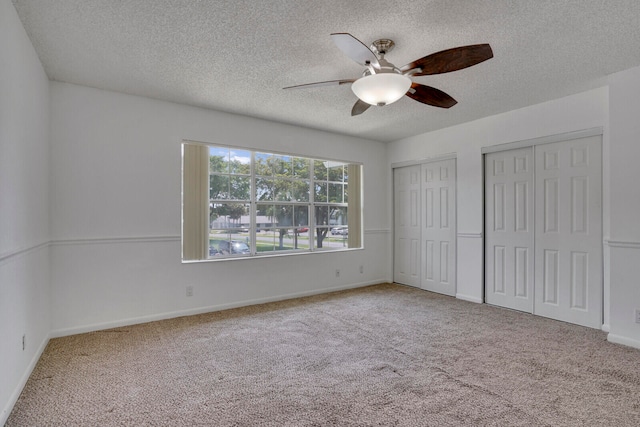 carpeted spare room featuring a textured ceiling and ceiling fan