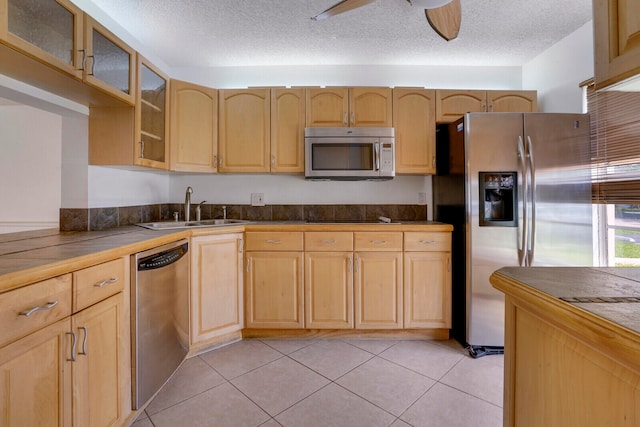 kitchen featuring ceiling fan, light tile floors, appliances with stainless steel finishes, sink, and a textured ceiling