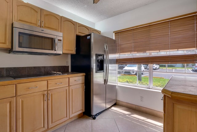 kitchen featuring tile counters, stainless steel appliances, a textured ceiling, and light tile floors