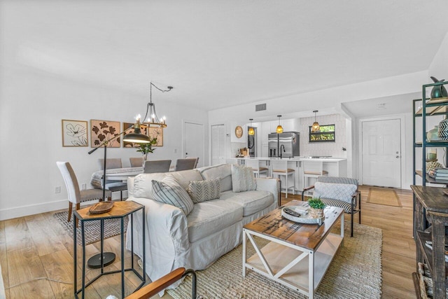 living room with a notable chandelier and light hardwood / wood-style flooring