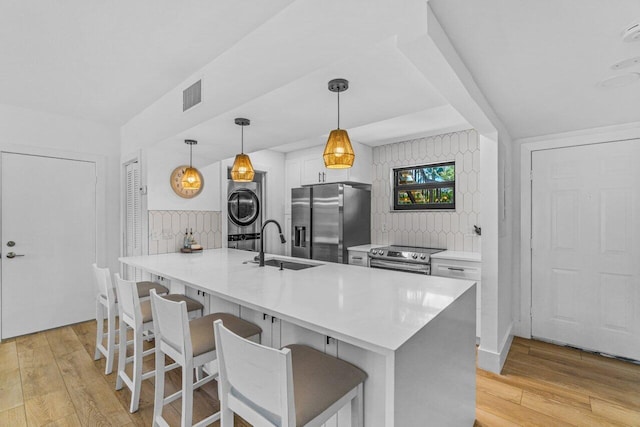 kitchen featuring white cabinets, sink, light wood-type flooring, appliances with stainless steel finishes, and decorative light fixtures