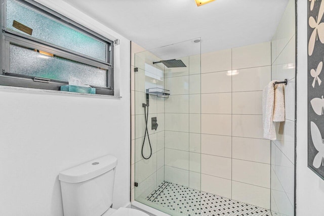 bathroom with a tile shower and toilet