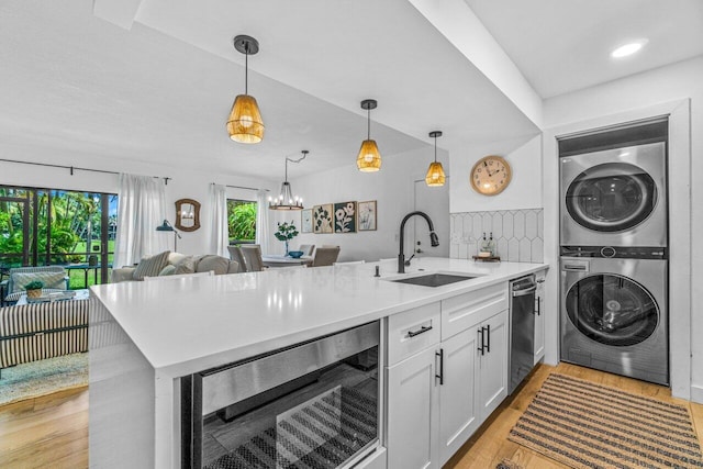 kitchen featuring wine cooler, sink, light hardwood / wood-style flooring, stacked washer and clothes dryer, and white cabinetry