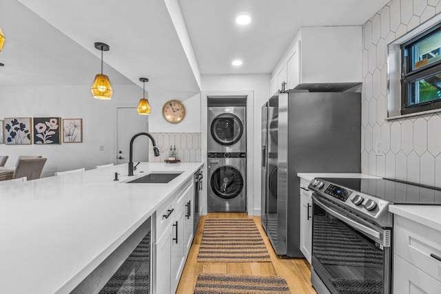 kitchen featuring sink, white cabinetry, stacked washer and dryer, and appliances with stainless steel finishes