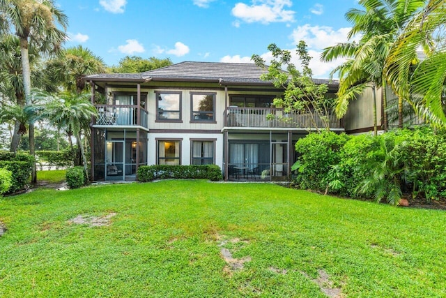 rear view of property featuring a balcony and a lawn