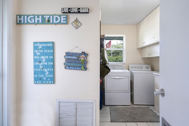 laundry room with light tile patterned floors, washer and dryer, and cabinets