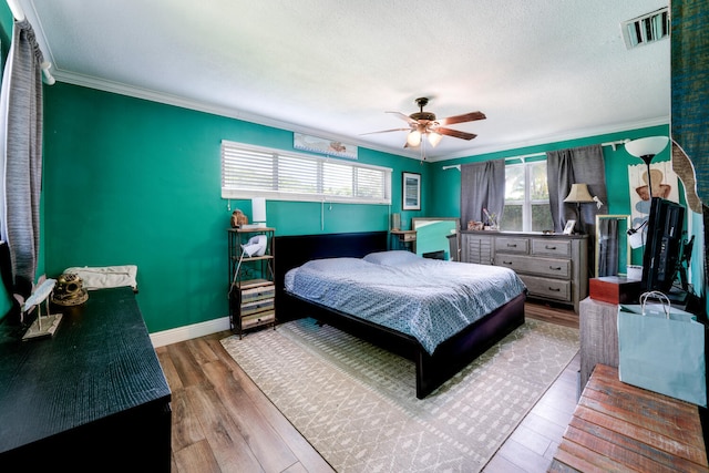 bedroom featuring a textured ceiling, ornamental molding, ceiling fan, and hardwood / wood-style flooring